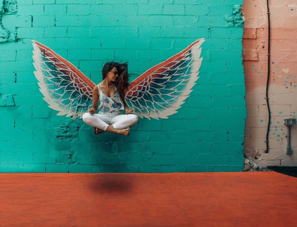 Envidia chica sentada de rodillas en una pared con un dibujo de una mariposa